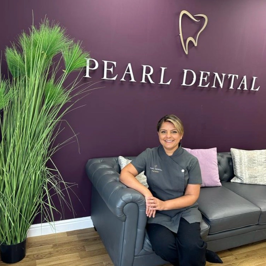Dr Narinder Khroud in the Pearl Dental reception beneath the practice sign