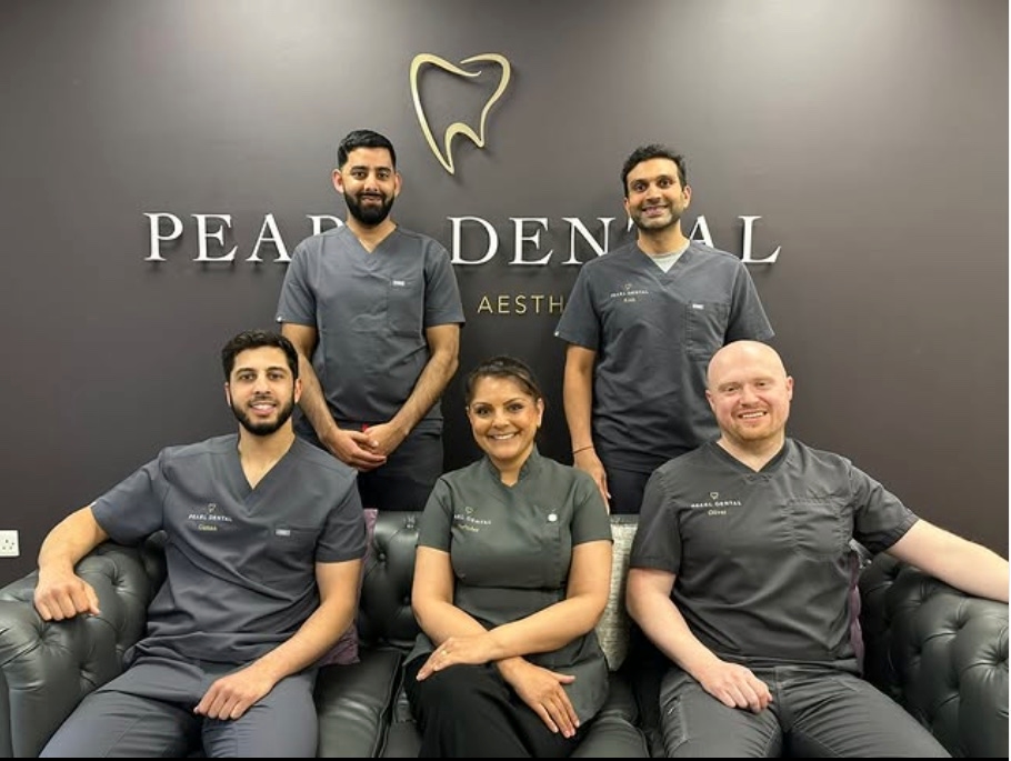 Five of the Pearl Dental clinical team beneath the gold tooth sign